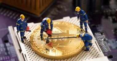 Miniaturas de homens em cima de moeda de Bitcoin gigante fazendo medição pela metade