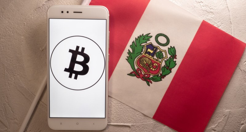 Celular com logo do Bitcoin à frente de bandeira do Peu