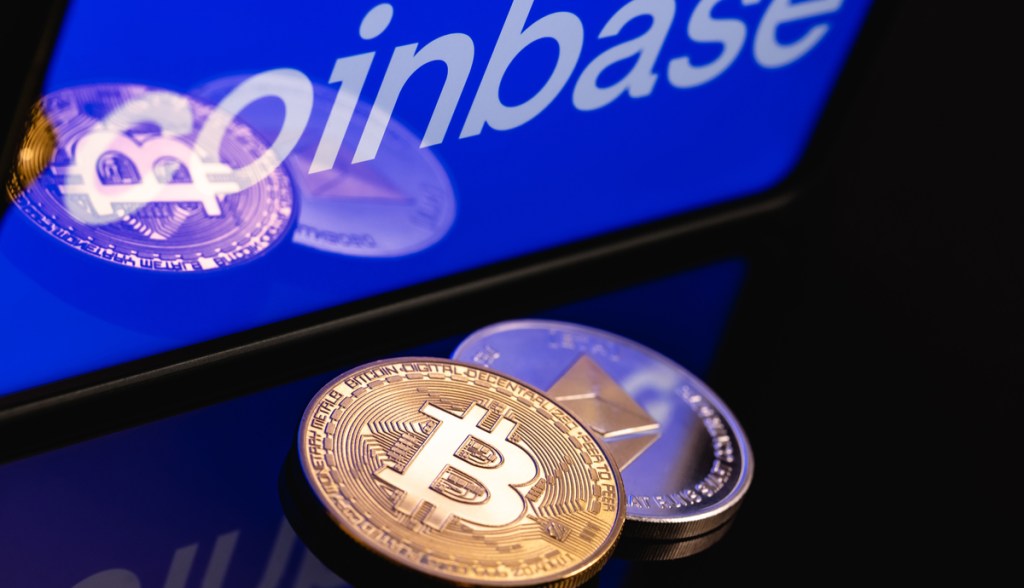 Moeda de bitcoin e etehreum à frente de tela com logo da Coinbase