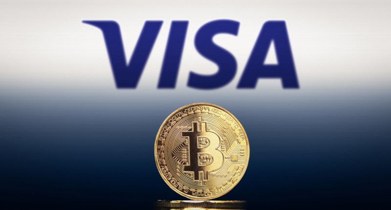 Logotipo da Visa acima de moeda de Bitcoin