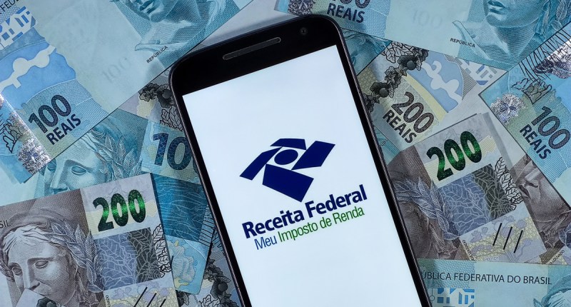 Celular com logotipo da Receita Federal sobre notas de reais