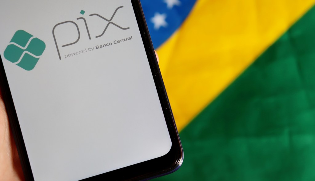 Celular com logo do Pix sob bandeira do Brasil
