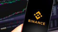 Celular com logo da Binance e gráfico no fundo