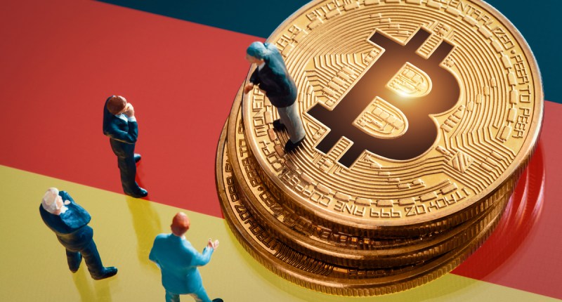 miniaturas de homens e moedas de bitcoin em cima de bandeira da Alemanha