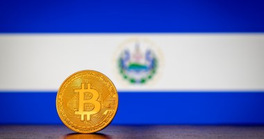 Moeda de Bitcoin à frente de bandeira de El Salvador