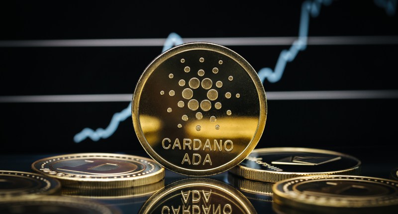 Moeda dourada com logo da Cardano na rente de gráfico com alta