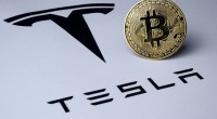 Moeda de Bitcoin sobre logomarca da Tesla