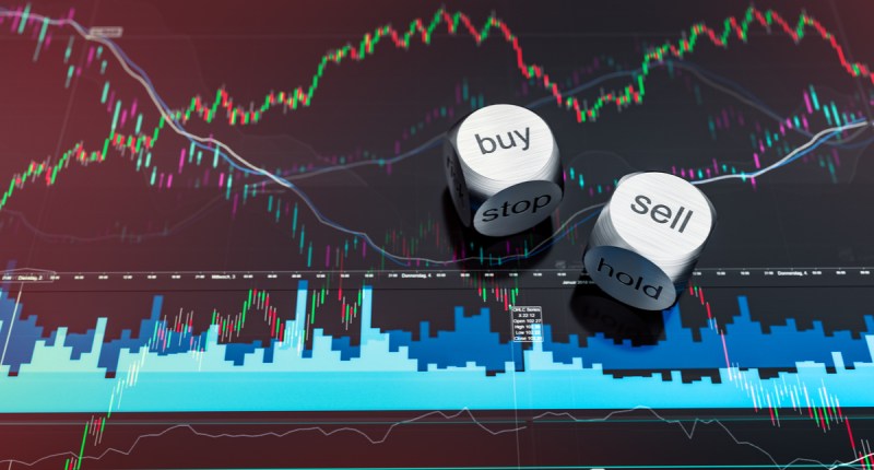 Dados metálicos com indicação buy e sell em cima de tela de trading