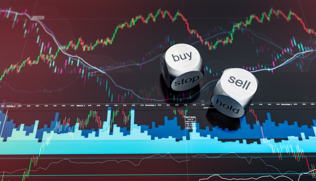 Dados metálicos com indicação buy e sell em cima de tela de trading
