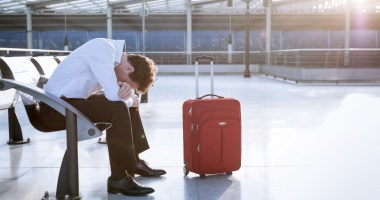 Homem triste sentado em um banco de aeroporto