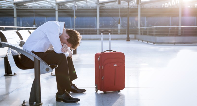 Homem triste sentado em um banco de aeroporto