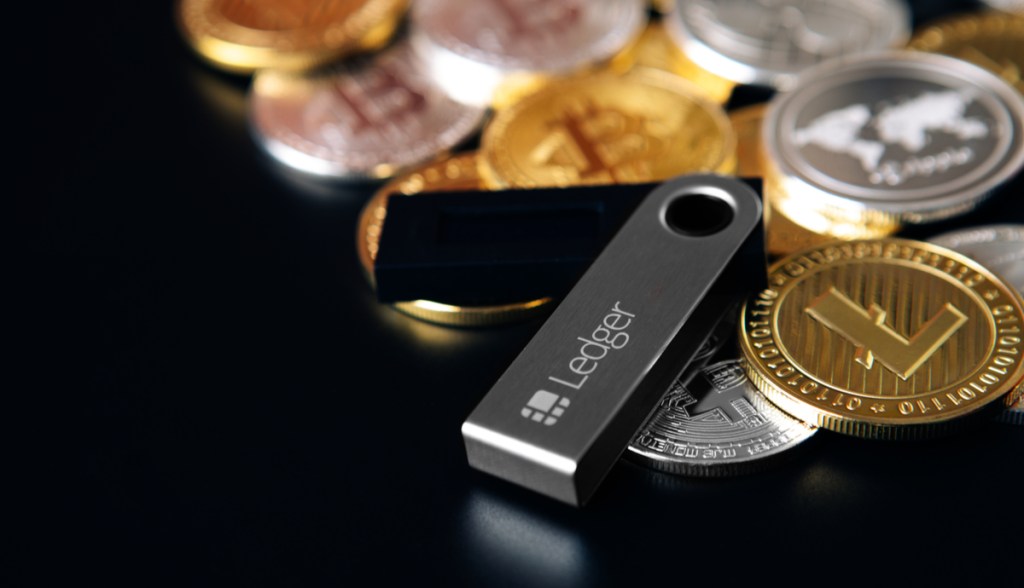 carteira física da ledger e criptomoedas ao fundo preto