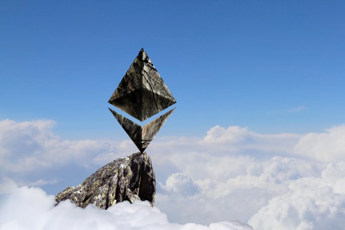 Logo do Ethereum é exibido com uma textura de pedra no topo de uma montanha, acima das nuvens