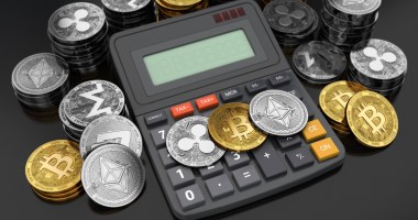 várias criptomoedas e uma calculadora sob uma mesa.jpg