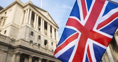 Bandeira do Reino Unido em destaque e o prédio do Banco da Inglaterra em desfoque ao fundo