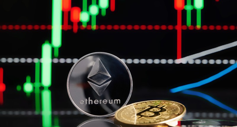 Moedas de Ethereum e Bitcoin em frente a um gráfico de candles em uma tela