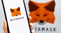 Mão segurando celular com o logo da carteira de criptomoedas MetaMask