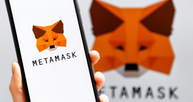 Mão segurando celular com o logo da carteira de criptomoedas MetaMask