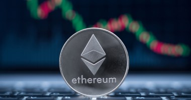 Moeda prateada de Ethereum (ETH) em frente a um gŕafico de preço com candles em queda