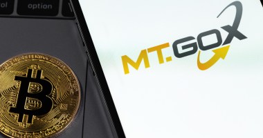 moeda de bitcoin ao lado de celular com logo da mt gox