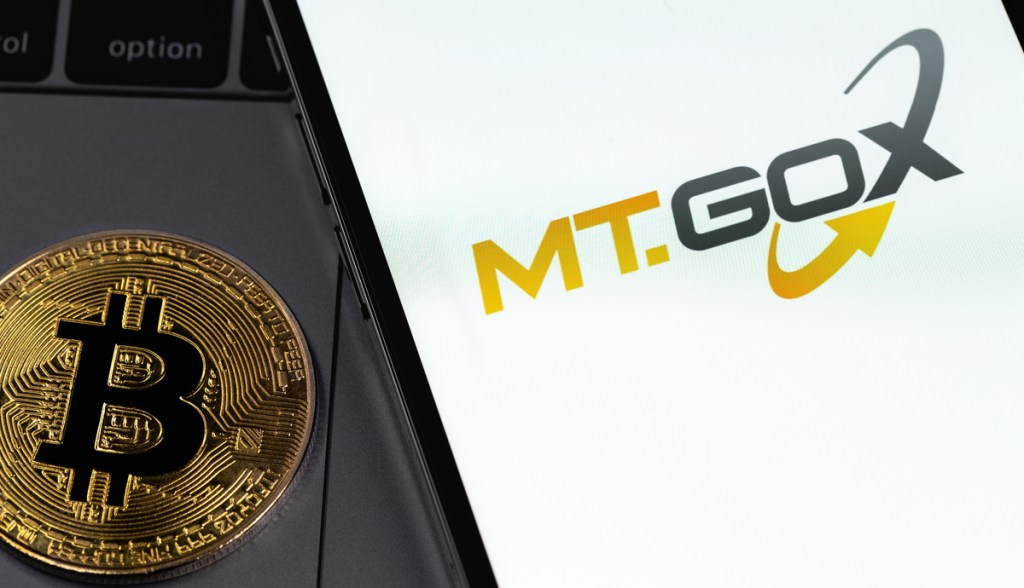 moeda de bitcoin ao lado de celular com logo da mt gox
