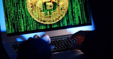 Tela de computador que mostra moeda de bitcoin em meio a traços matrix