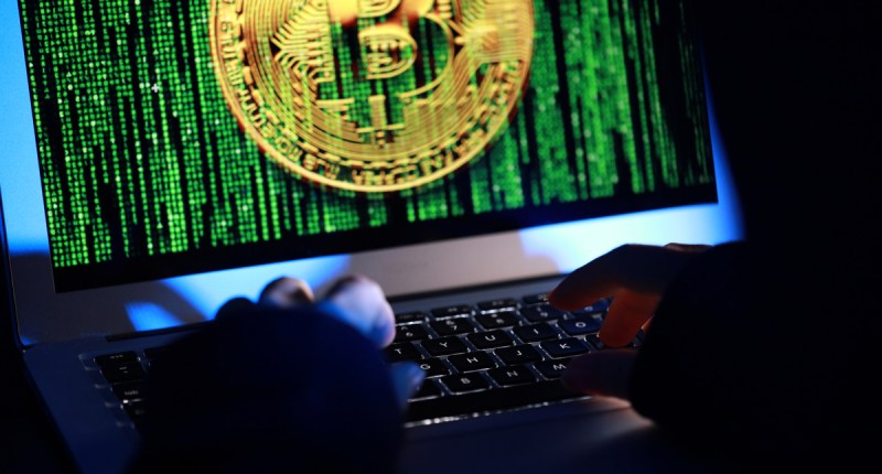 Tela de computador que mostra moeda de bitcoin em meio a traços matrix