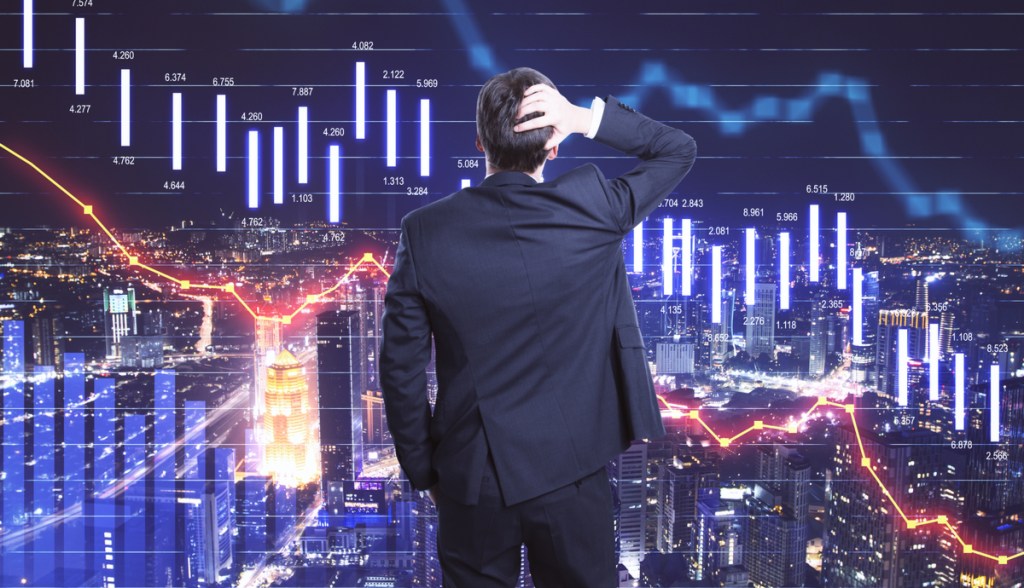 Investidor e telas de mercado em baixa