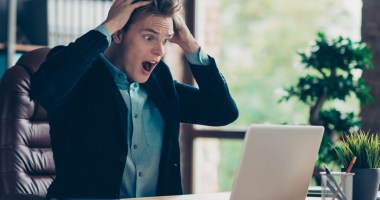 Homem tomando susto olhando pro computador