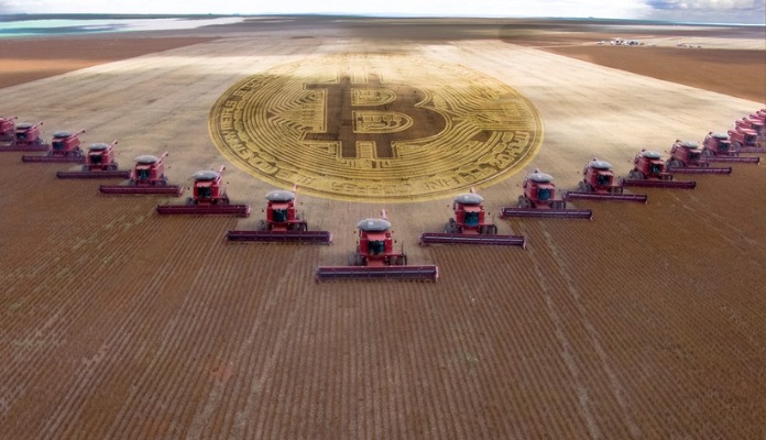Símbolo do bitcoin em meio a máquinas agrícolas e plantação