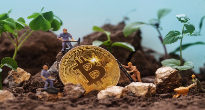 miniaturas de pessoas minerando bitcoin em meio a pedras e folhagens