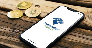 Celular com logo da Receita Federal e Bitcoin e criptomoedas do lado