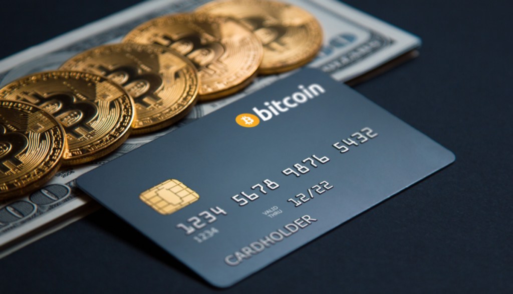 Moedas de bitcoin e cartão com o tema em cima de dólares sob mesa escura