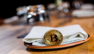 Moeda de bitcoin apoiada em um guardanapo dentro de um prato