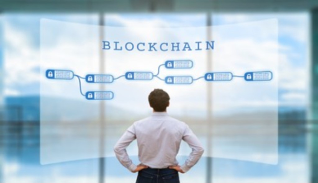 De costas, homem olha para grande tela com solução blockchain
