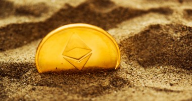 Moeda Ethereum ETH parcialmente enterrada na areia