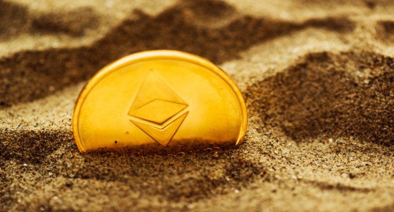 Moeda Ethereum ETH parcialmente enterrada na areia