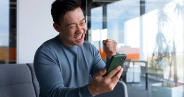 Homem comemora olhando para a tela do celular