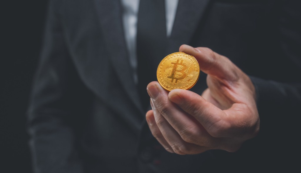Mão estendendo uma moeda de bitcoin