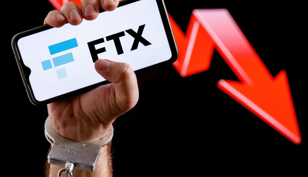 Homem algemado segura celular com logo da FTX