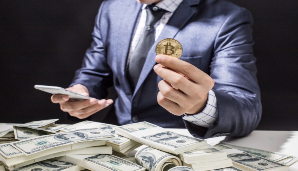 Homem sentado à mesa negociando bitcoin e dólar