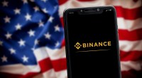 logo a binance no celular e bandeira dos EUA no fundo