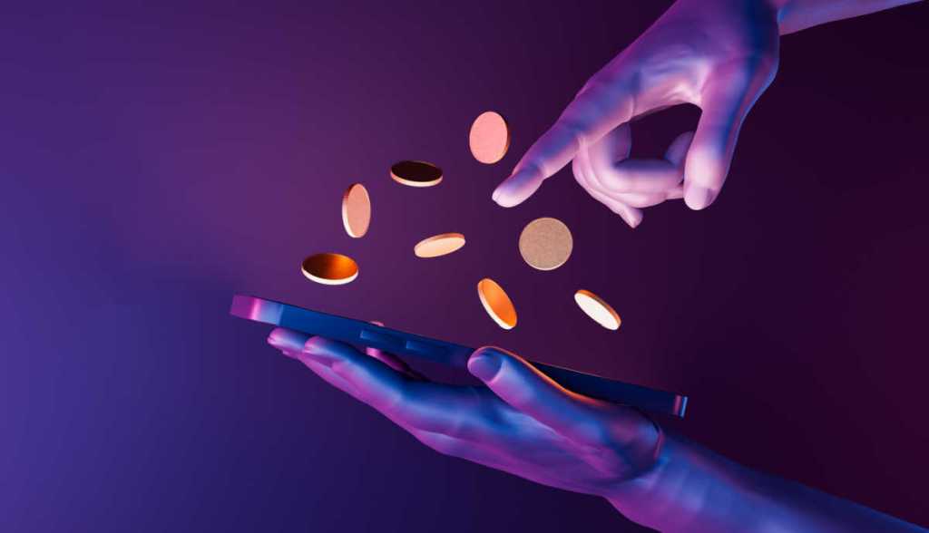 Arte digital mostra mãos operando um celular que projeta moedas