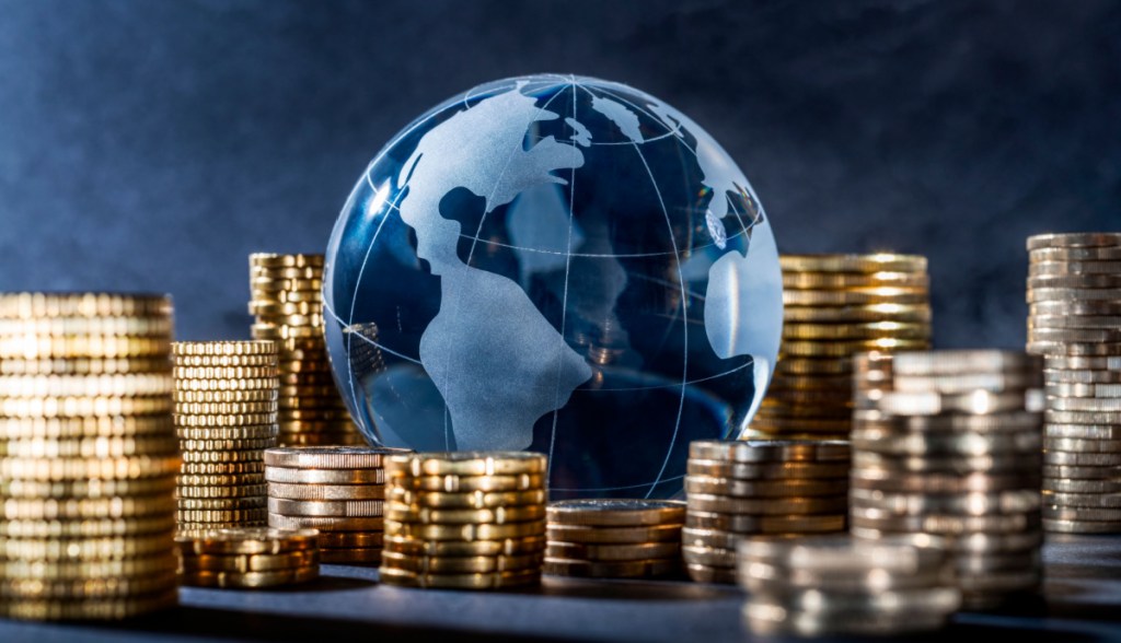 Globo azul mapeado envolto a montes de moedas douradas