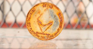 Moeda de Ethereum ETH enferrujada à frente de uma grade de proteção