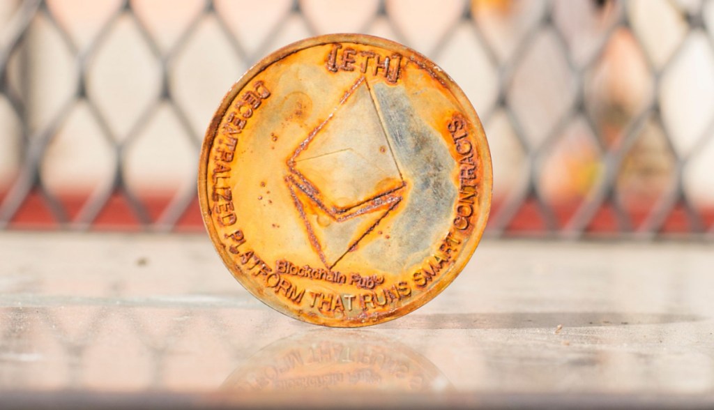 Moeda de Ethereum ETH enferrujada à frente de uma grade de proteção