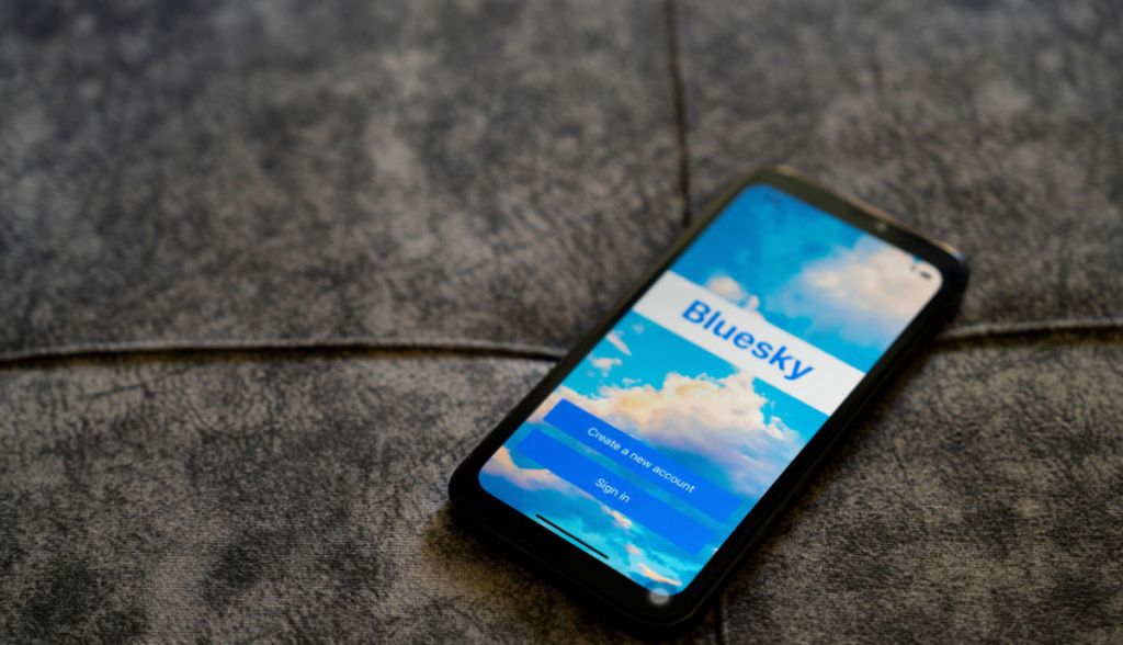 Smartphone sob sofá de camurça mostra logotipo da Bluesky