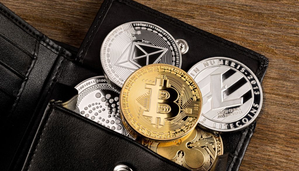 Carteira de couro aberta mostra várias criptomoedas físicas