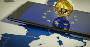 Moeda de Bitcoin em cima de celular com logo da UE União Europeia e em cima de mapa da Europa