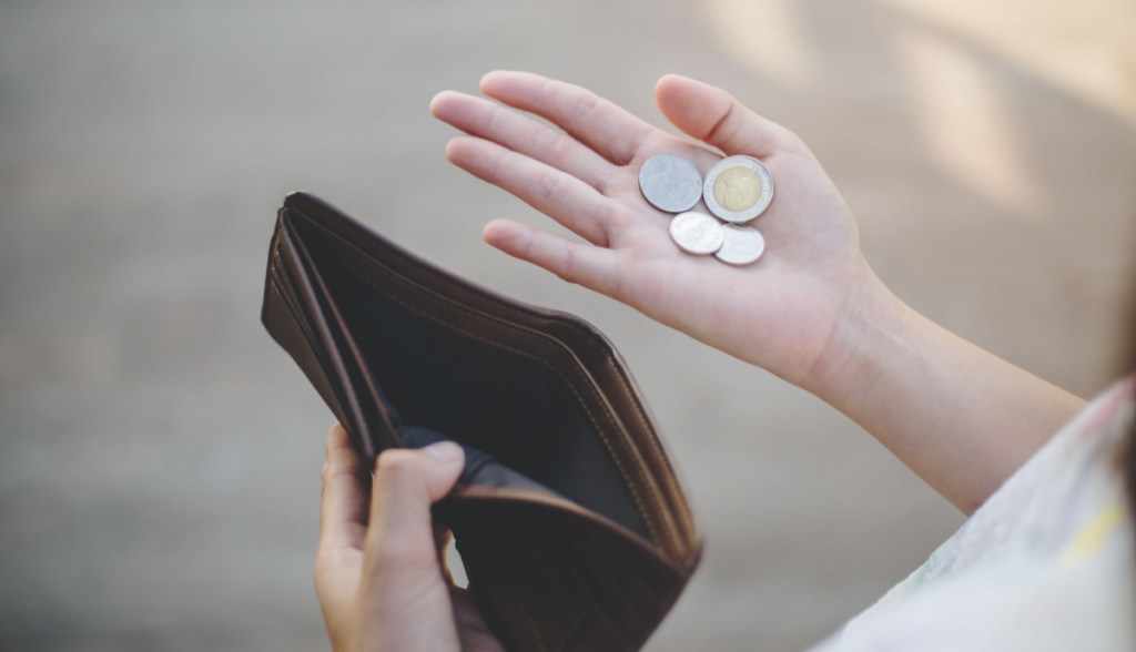 Mulher segura poucas moedas - outra mão segura carteira vazia